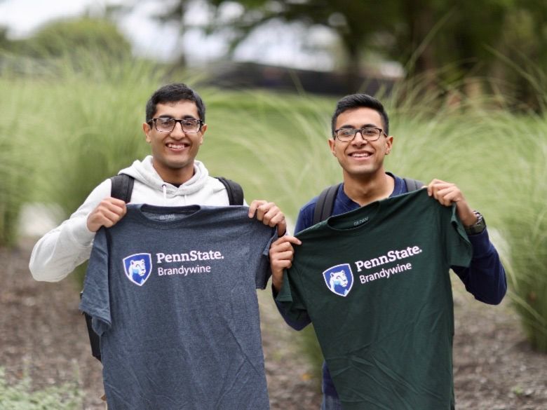 Two male students holding up Penn State Brandywine tee shirts.