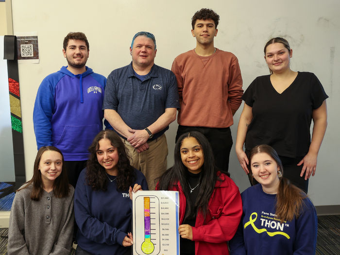 students with staff member smiling with THON total thermometer