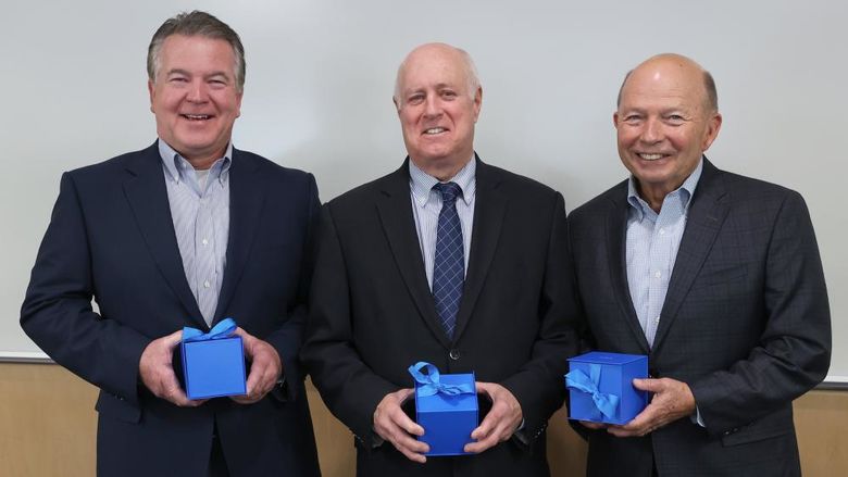 Three men hold boxes containing their gifts.