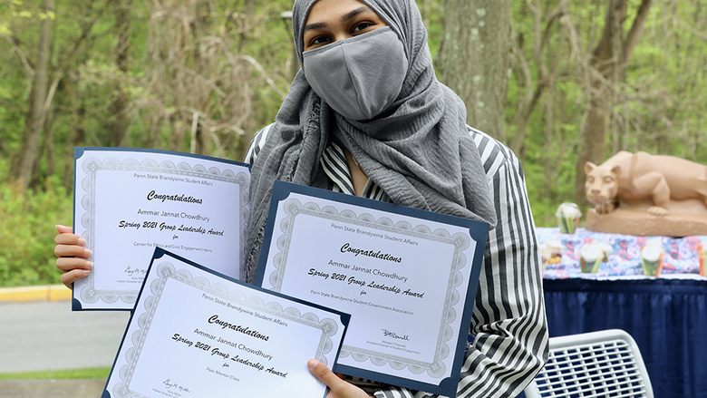 Female student sharing her three award certificates.