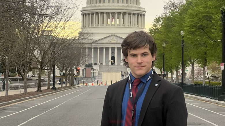 A male stands on a street in front of the U.S. Capitol
