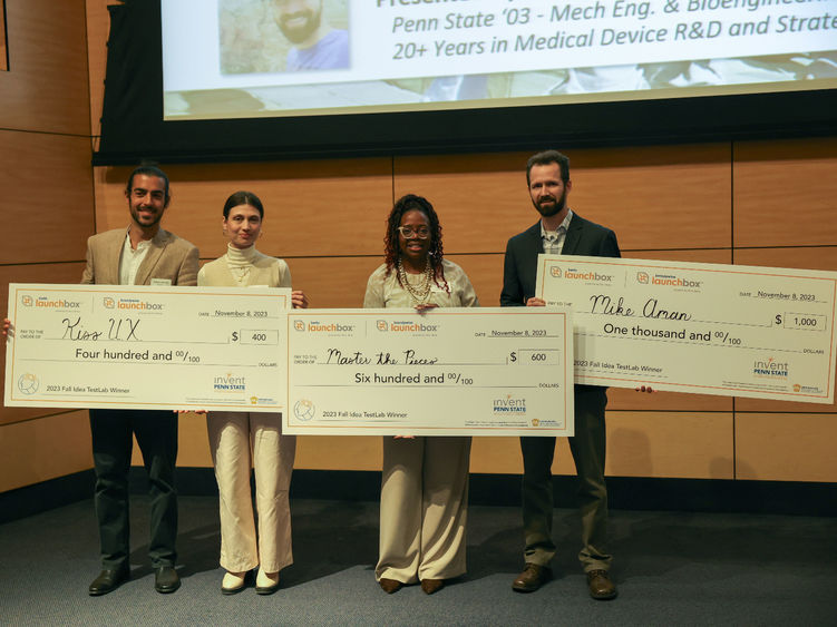winners of idea TestLab competition standing on stage with large checks for $400, $600 and $1000