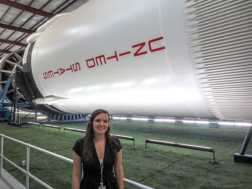 Sarah Huppman standing in front of a rocket at NASA