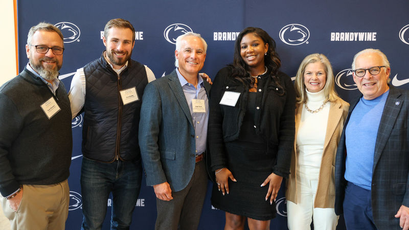 student with advisory board members pose for a photo