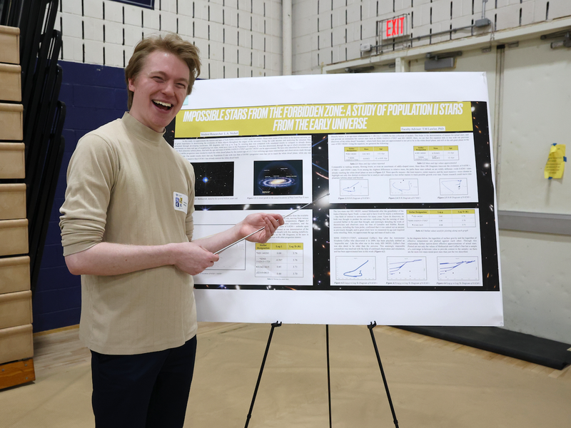 Student holding pointer while presenting poster on stars