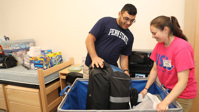 Orientation leader, Tammy Katz, helps a student by pushing a cart full of items into his new dorm room.