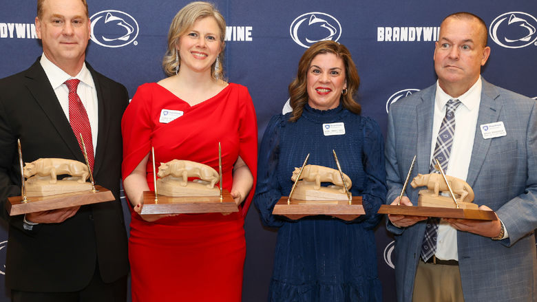 four people holding awards