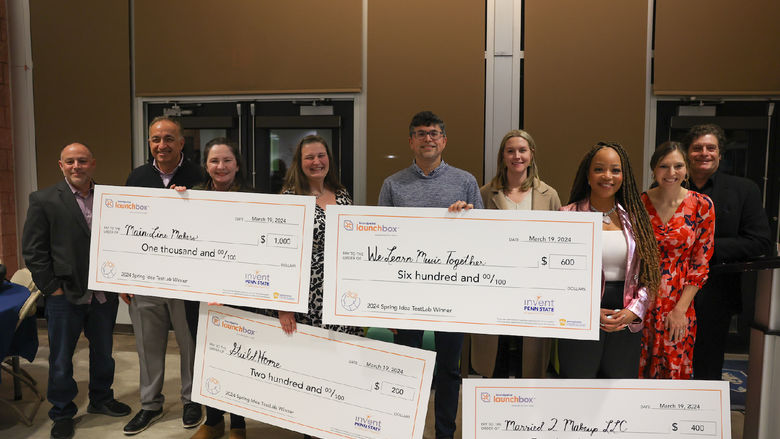 group of people holding large checks