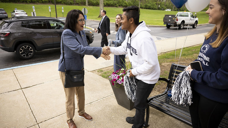 A woman shakes the hand of a male student.