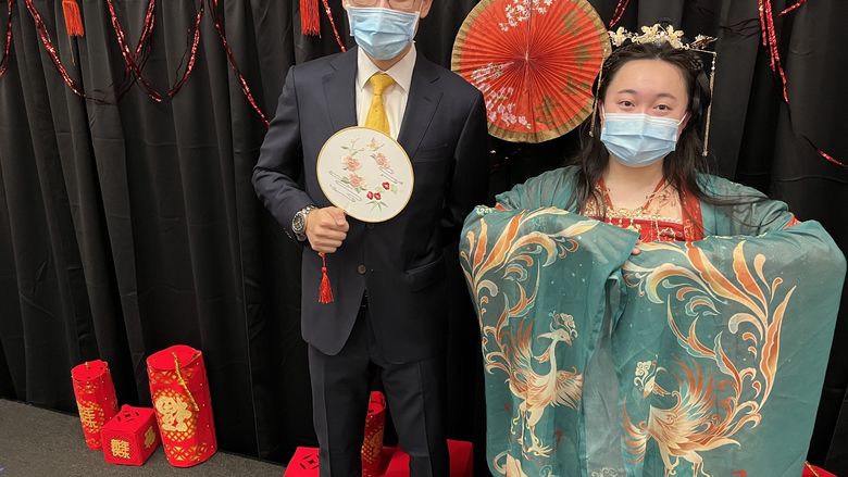 A male student wearing a suit and a female student wearing traditional Chinese clothing.