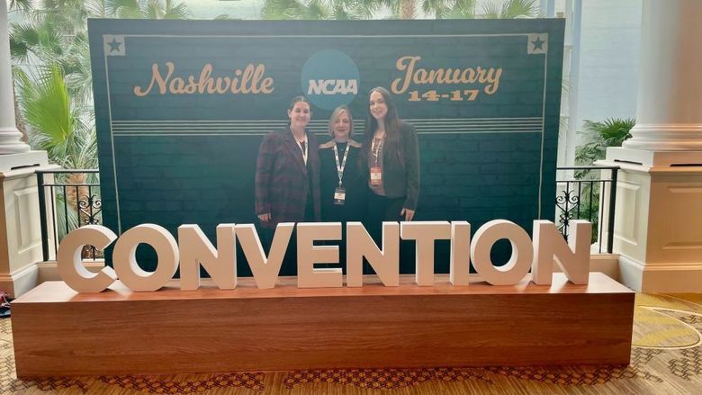 three women standing behind sign hat says Convention