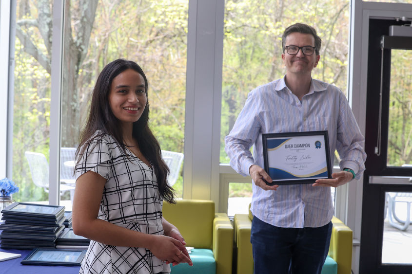 Two people stand with a framed certificate