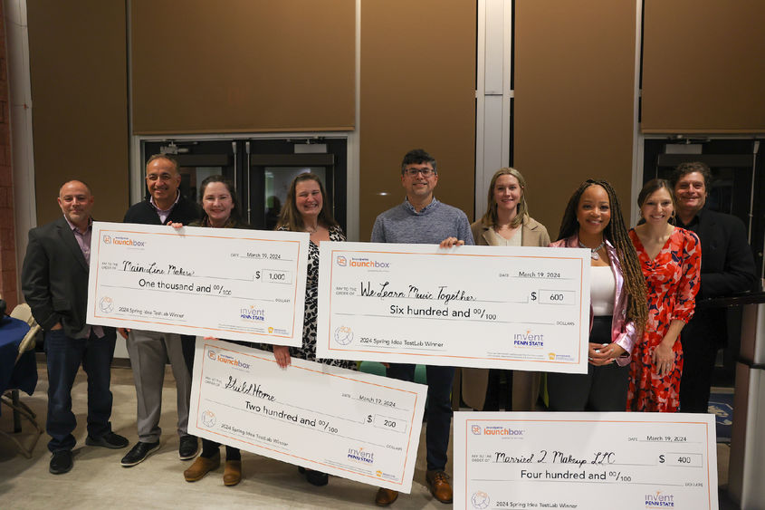 group of people holding large checks