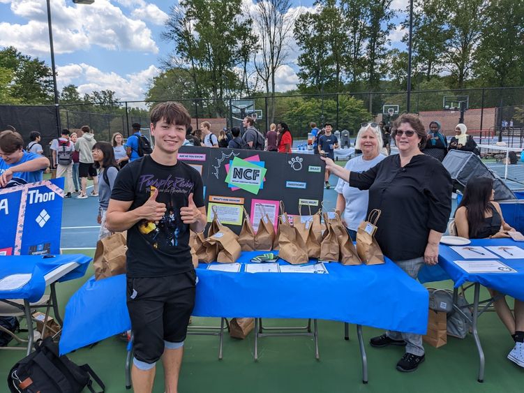 three people standing at a table on a tennis court