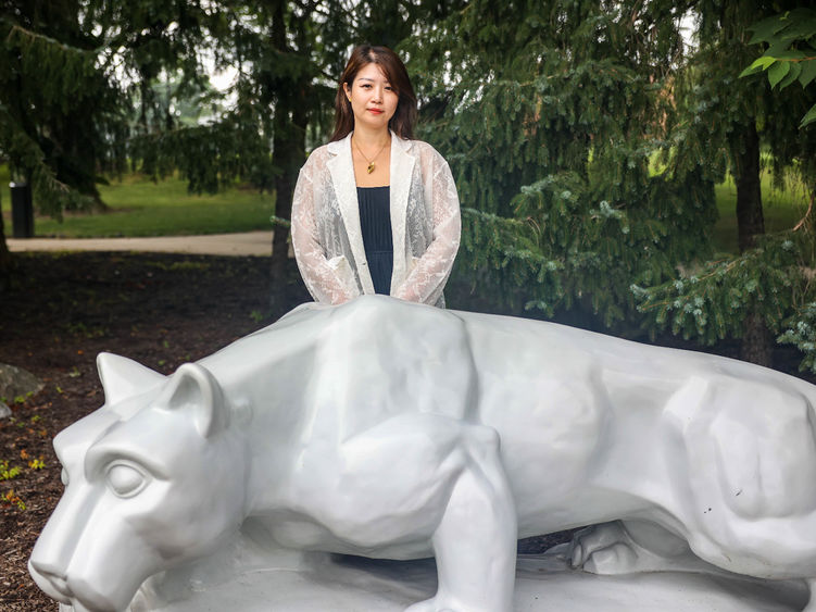 Luna Yang standing behind Nittany Lion shrine