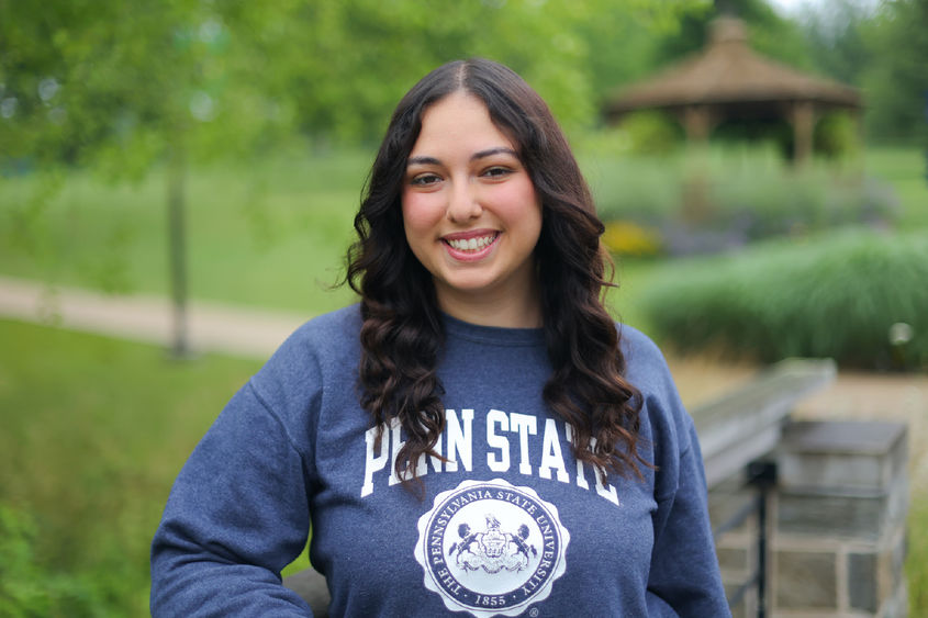 woman wearing blue Penn State sweatshirt leaning on a bridge