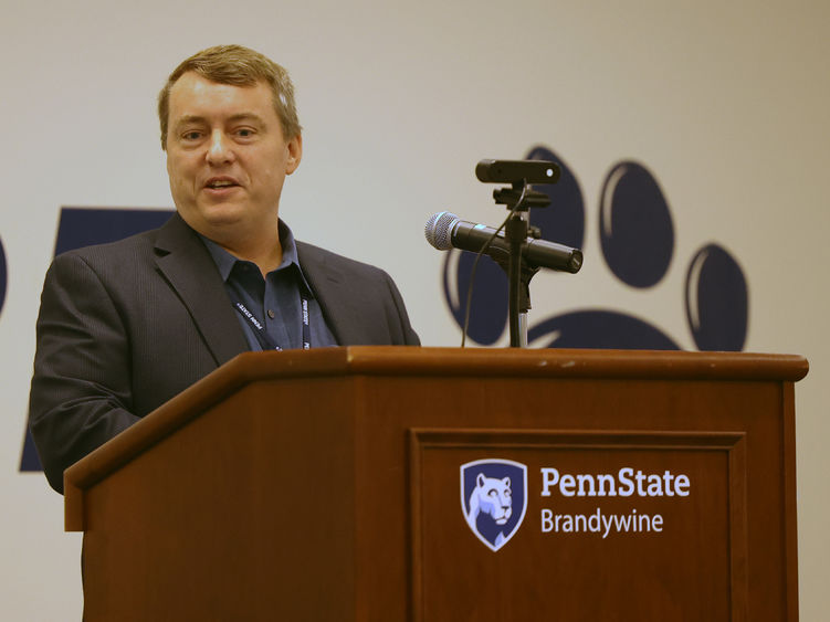 A male professor speaks at a lectern